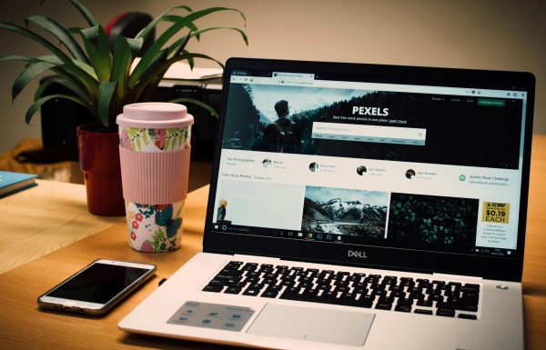 A tidy desk setting with a laptop showing a stock photo website and a smartphone.